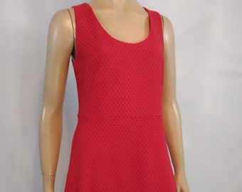 May include: A sleeveless red dress with a textured pattern. The dress has a scoop neckline and a slightly flared skirt.