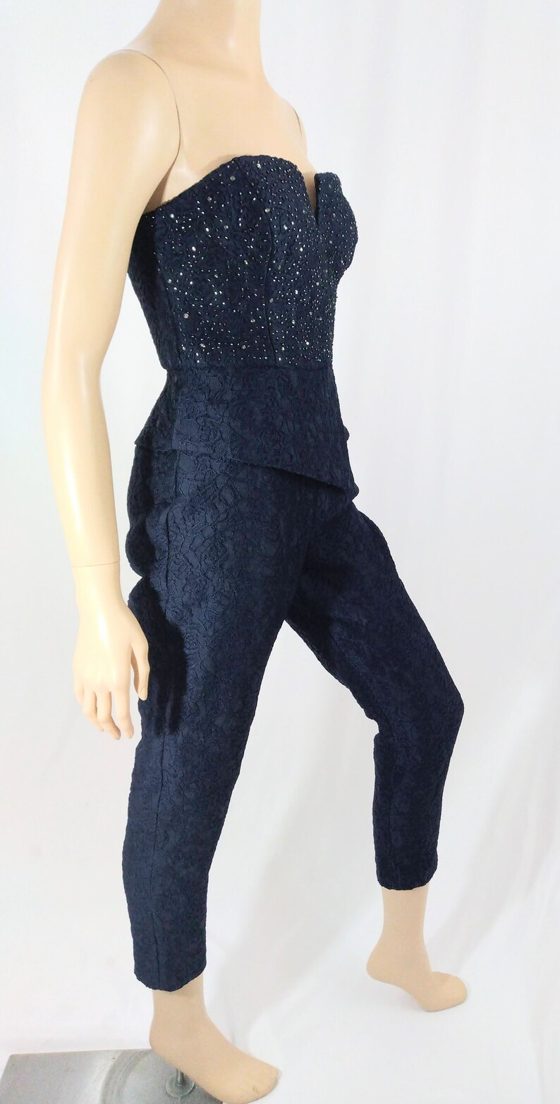 May include: A navy blue strapless jumpsuit with a lace pattern and a beaded bodice.