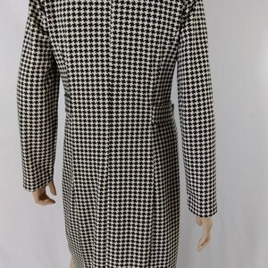 May include: A black and white houndstooth patterned dress with a long sleeve and a high neckline.