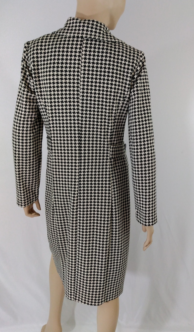 May include: A black and white houndstooth patterned dress with a long sleeve and a high neckline.