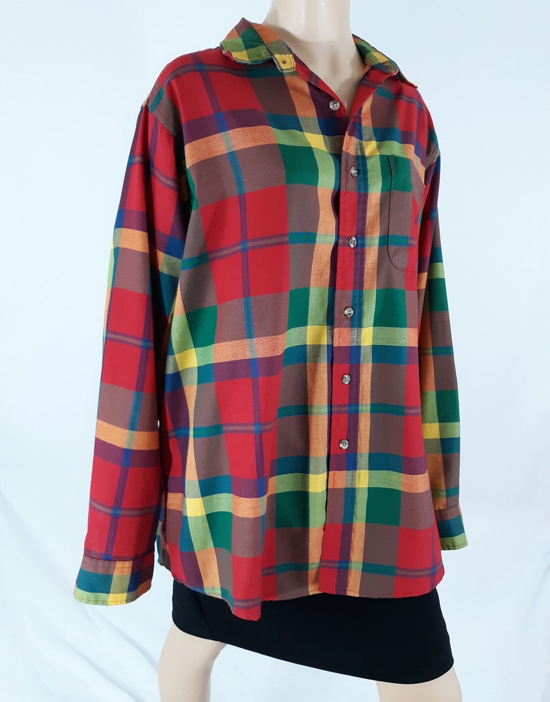 May include: A long-sleeved plaid shirt with a button-up front. The shirt is red, green, yellow, and brown.