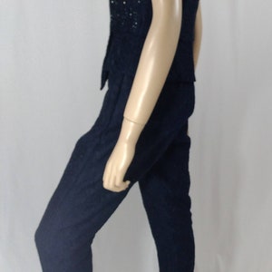May include: A strapless black jumpsuit with a sequined bodice. The jumpsuit is made of a textured fabric and has a fitted silhouette.