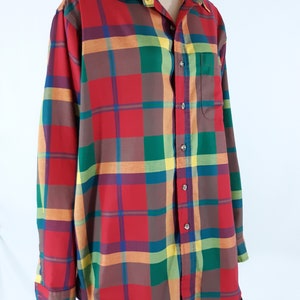 May include: A long-sleeved button-down shirt with a plaid pattern in shades of red, green, orange, and yellow.
