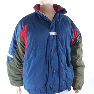 May include: A blue, red, and green color block puffer jacket with a zipper and snap closure. The jacket has a stand-up collar and a drawstring waist.