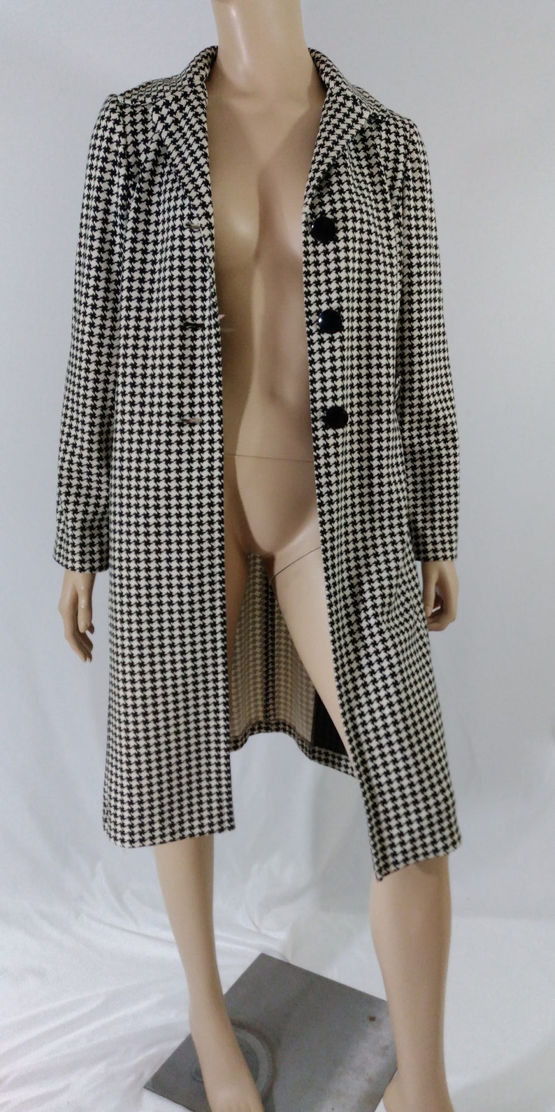 May include: A long black and white houndstooth patterned coat with black buttons.