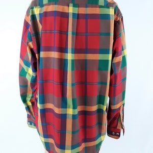 May include: A long-sleeved button-down shirt with a plaid pattern in red, green, yellow, and brown.