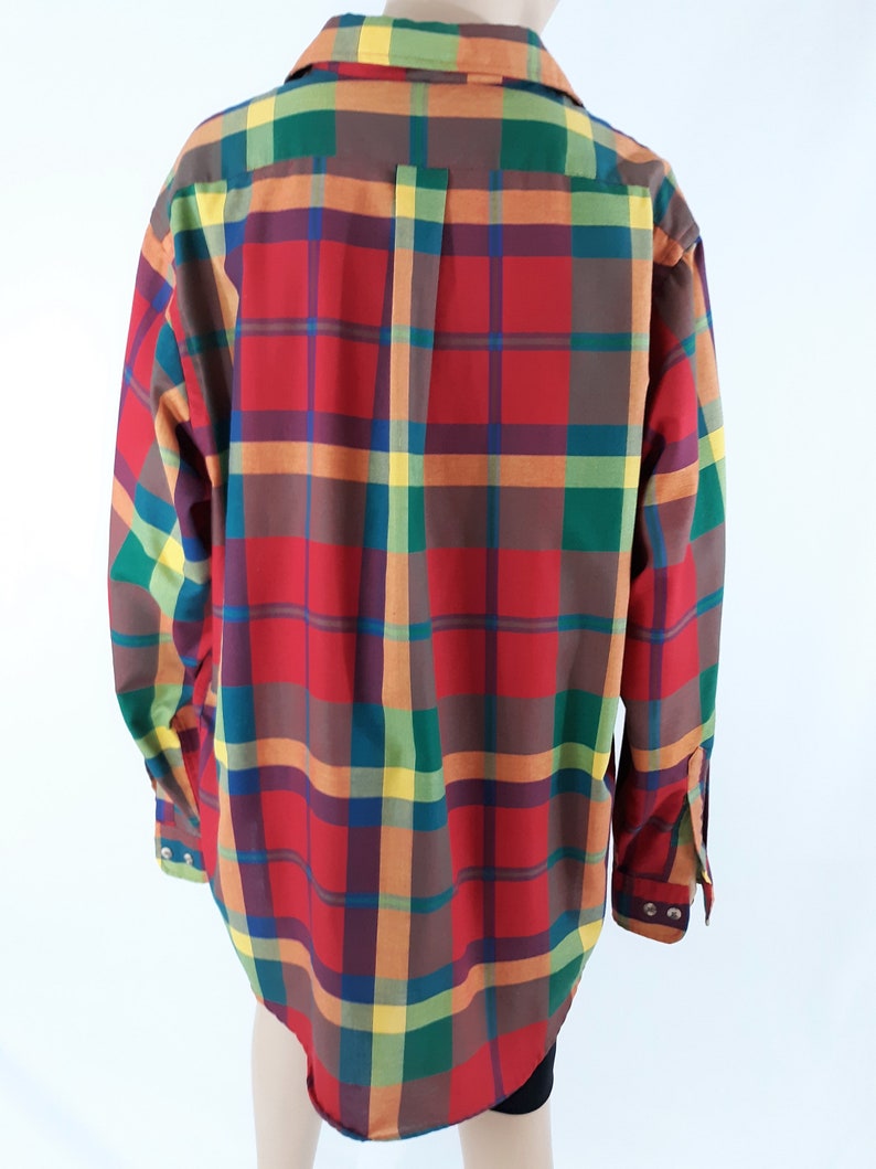 May include: A long-sleeved button-down shirt with a plaid pattern in red, green, yellow, and brown.