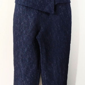May include: A navy blue jumpsuit with a strapless bodice and a floral pattern. The bodice is embellished with rhinestones.