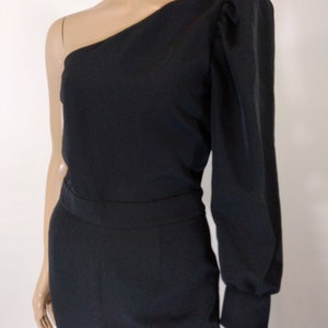 May include: A black one-shoulder jumpsuit with a long sleeve on one side and a puff sleeve on the other side.