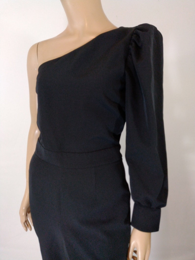 May include: A black one-shoulder jumpsuit with a long sleeve on one side and a puff sleeve on the other side.