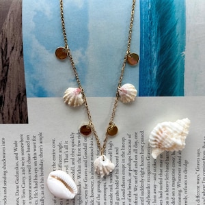 Könnte beinhalten: Goldfarbene Halskette mit kleinen, runden Anhängern und zarten Muschelanhängern. Dieses Schmuckstück im Strand-Look ist perfekt, um jedem Outfit einen Hauch von Küstencharme zu verleihen.