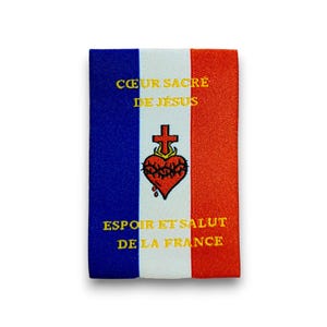 Peut inclure: Un écusson rectangulaire en tissu avec un motif tricolore vertical bleu, blanc et rouge. Le centre blanc présente un Sacré-Cœur rouge brodé avec une croix et le texte jaune CŒUR SACRÉ DE JÉSUS et ESPOIR ET SALUT DE LA FRANCE.