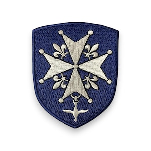 Peut inclure: Écusson brodé bleu marine en forme de bouclier. Le patch présente un motif de croix blanche avec des éléments de fleur de lys et une colombe en bas. Le design est détaillé et le patch a un aspect texturé.