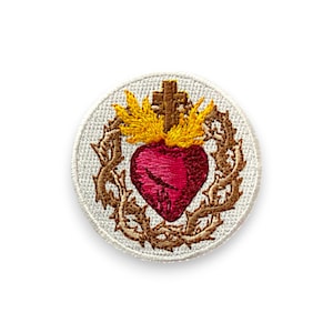 May include: Embroidered patch featuring a red heart with a cross and flames, surrounded by a brown thorny wreath. The patch is circular with a white border, suitable for sewing or ironing onto fabric.