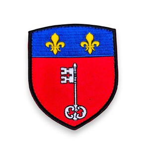 Peut inclure: Un écusson brodé rouge et bleu avec une clé et deux fleurs de lys. L'écusson est en forme de bouclier et a une bordure noire.