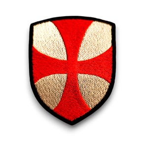 Peut inclure: Un patch en forme de bouclier avec une croix rouge brodée sur un fond doré. Le patch a une bordure noire.