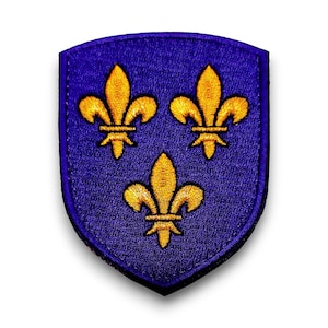 Peut inclure: Écusson en forme de bouclier avec un fond bleu foncé. Trois symboles de fleur de lys dorés sont brodés sur l'écusson. L'écusson a une bordure bleu foncé, probablement un emblème ou un insigne.