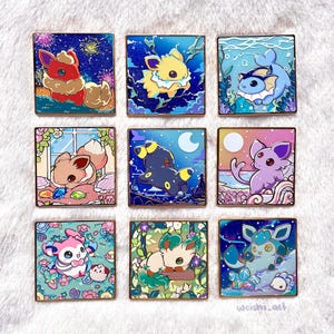 Könnte beinhalten: Neun quadratische Emaille-Anstecknadeln mit goldenen Rändern, die jeweils einen anderen Pokémon-Charakter in einer einzigartigen Szene zeigen. Die Anstecknadeln weisen leuchtende Farben und detaillierte Kunstwerke auf, mit Schauplätzen wie Sternennächten und Unterwasserumgebungen.