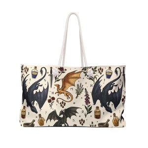 May include: Cream-colored tote bag with a repeating pattern of dragons, potion bottles, daggers, and floral elements. The bag has a white rope handle and is designed for carrying items. The dragon illustrations are in black, gold, and gray.