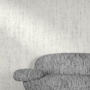 May include: A modern gray sofa with a textured fabric, featuring a rounded back and armrest. The sofa is set against a textured white wall, creating a minimalist and contemporary aesthetic. The design is suitable for living room decor.