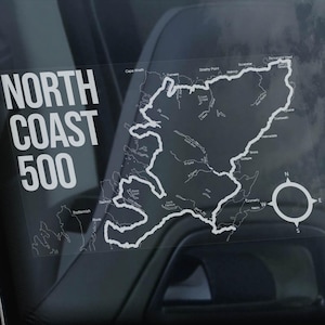Può includere: Un adesivo bianco sul lunotto posteriore di un'auto nera con il testo "NORTH COAST 500" e una mappa di un percorso con una bussola.