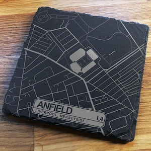 Può includere: Un sottobicchiere quadrato in ardesia nera con una mappa dettagliata dell'area di Anfield. Include il nome "ANFIELD" e i dettagli della posizione. Poggia su una superficie di legno.