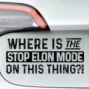 May include: A rectangular bumper sticker with the text "WHERE IS THE STOP ELON MODE ON THIS THING?!" in black, distressed font. The sticker is attached to the rear of a white car, near the taillight.