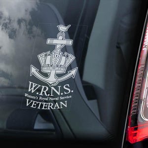 May include: A clear decal featuring the Women's Royal Naval Service (W.R.N.S.) emblem, including an anchor, crown, and ship design, with the text "VETERAN". The decal is affixed to a car window, with a cloudy sky visible.