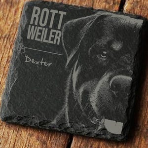 Könnte beinhalten: Ein quadratischer, dunkelgrauer Schieferuntersetzer mit einem Rottweiler-Hundeporträt. Der Text "ROTTWEILER" steht oben, mit "Dexter" unter einem Pfotenabdruck. Das Gesicht des Hundes ist detailliert graviert.