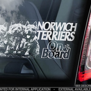 以下が含まれることがあります： 3匹のノーウィッチテリアの白黒画像と「NORWICH TERRIERS On Board」というテキストが書かれた白い車の窓用ステッカーです。