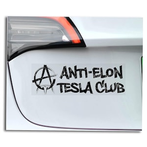 May include: A white car with a black bumper sticker that says "Anti-Elon Tesla Club" with an anarchy symbol.