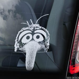 Może przedstawiać: Biała naklejka winylowa z postacią Muppety z dużym nosem i dużymi oczami. Postać jest znana jako Animal z Muppetów.