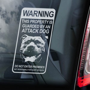 Op de afbeelding: Wit waarschuwingsbord met zwarte tekst en een zwart-witte afbeelding van een hond. Het bord luidt "WARNING THIS PROPERTY IS GUARDED BY AN ATTACK DOG DO NOT ENTER PREMISES NOT RESPONSIBLE FOR INJURY OR DEATH."