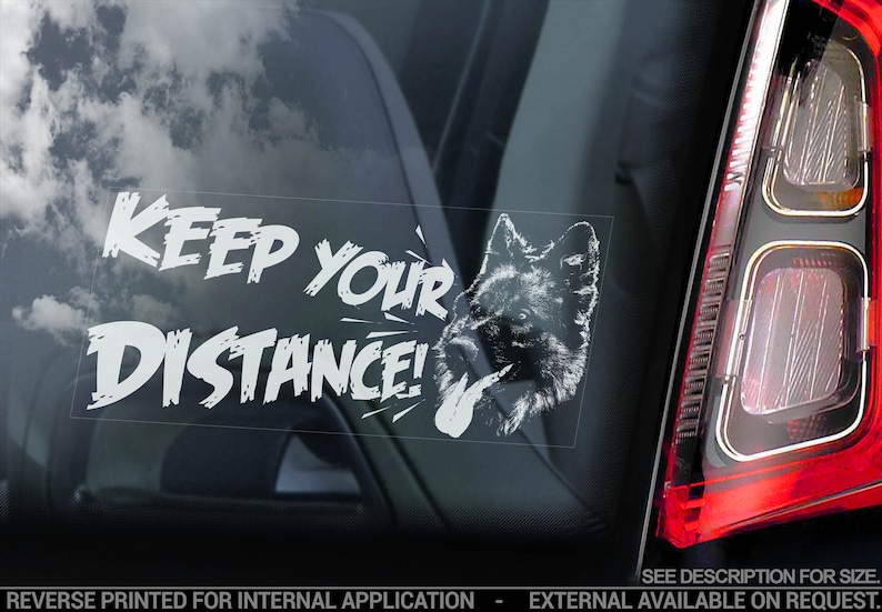 May include: White vinyl car sticker with the text "KEEP YOUR DISTANCE!" in a bold, handwritten font. A white silhouette of a wolf's head is to the right of the text.