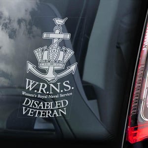 Könnte beinhalten: Weißer Aufkleber mit dem Emblem des Women's Royal Naval Service (W.R.N.S.), Anker, Krone und Vogel, mit dem Text "DISABLED VETERAN". Der Aufkleber befindet sich auf einer Autoscheibe, mit einem roten Rücklicht.