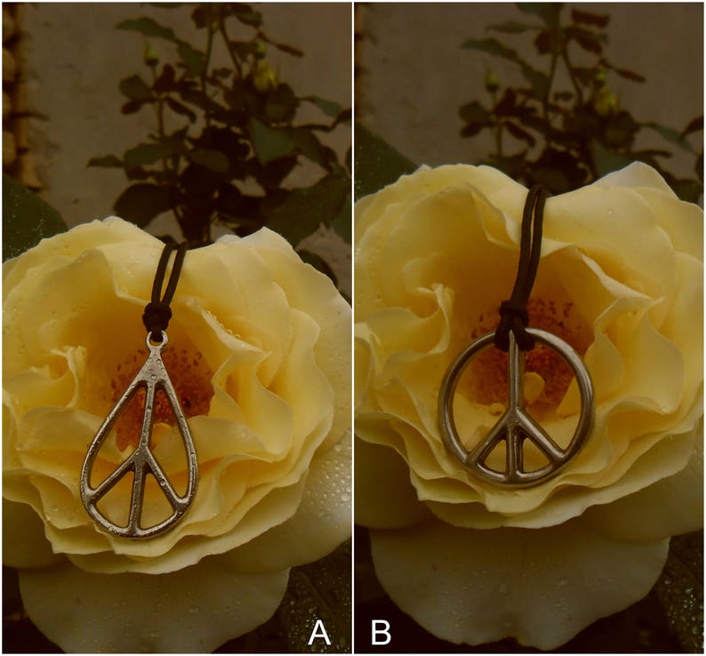 May include: A silver peace sign pendant necklace on a black cord, resting on a yellow rose.