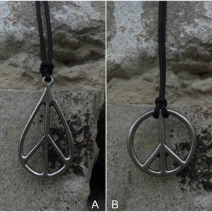 May include: Two silver peace sign pendants on black cords. The pendant on the left is a teardrop shape, while the pendant on the right is a circle.