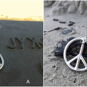May include: Two images of a silver peace sign keychain. The first image shows the keychain on a dark surface with the word "JYKK" engraved on the surface. The second image shows the keychain on a sandy surface with a piece of driftwood.