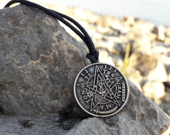 May include: A silver pendant necklace with a five-pointed star design. The star is surrounded by a circle with the words "1 2 3 TRA GRAM", and "1 2 TE TON MA", and symbols.