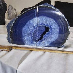 May include: A pair of blue agate bookends with a white and blue center. The bookends are cut from a large stone, revealing a detailed pattern. The edges are dark blue, and the center has a crystalline appearance.