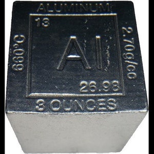 May include: A silver cube with the chemical symbol for aluminum, Al, and the atomic number 13. The cube also has the text "Aluminum", "2.70g/cc", "26.98", and "3 ounces" printed on it.