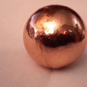 May include: A shiny, copper-colored sphere with a smooth, slightly textured surface.