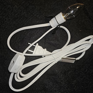 May include: White electrical cord with a white inline switch and a white plug. The cord has a clear light bulb attached to the end.