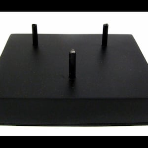 May include: Black rectangular display stand with three metal posts. The stand is made of wood and has a smooth, matte finish.