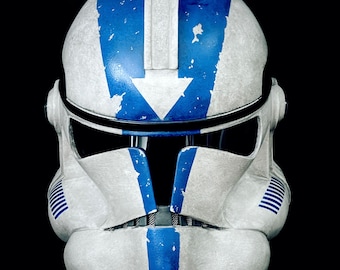 May include: A white and blue clone trooper helmet with a blue stripe down the center and a blue arrow on the top. The helmet has a weathered look with visible scratches and paint chips.