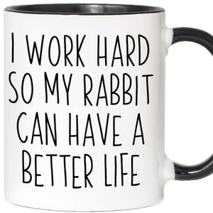 May include: White ceramic mug with a black interior and handle. The mug features the text "I WORK HARD SO MY RABBIT CAN HAVE A BETTER LIFE" in black, handwritten-style lettering. A fun gift for rabbit owners.