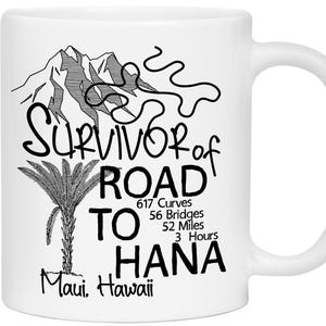 K&ouml;nnte beinhalten: Wei&szlig;e Keramiktasse mit schwarzem Grafikdesign. Das Design enth&auml;lt den Text "SURVIVOR of ROAD TO HANA" mit einem Berg, einer Palme und dem Text "617 Kurven, 56 Br&uuml;cken, 83.7 Kilometer, 3 Stunden". Die Worte "Maui, Hawaii" sind ebenfalls enthalten.