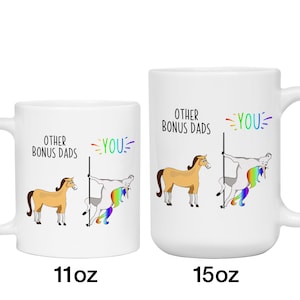 May include: White ceramic mugs with a humorous design. One mug is labeled "11oz" and the other "15oz". The design features a cartoon horse and a unicorn, with the text "OTHER BONUS DADS" and "YOU" in rainbow colors.