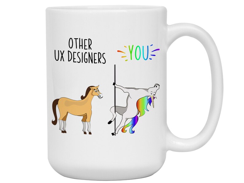 May include: White ceramic mug with a humorous design. The mug features a cartoon illustration comparing "Other UX Designers" to a horse and "YOU" to a unicorn, with rainbow accents. The mug has a large handle.