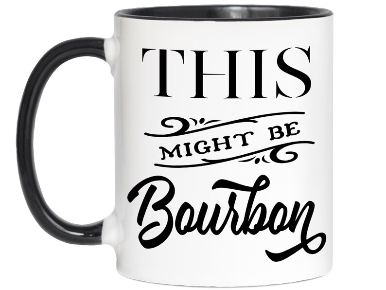 Puede incluir: Taza de cer&aacute;mica blanca con asa y borde negros. La taza presenta el texto "THIS MIGHT BE Bourbon" en negro, con letras estilizadas. Una l&iacute;nea decorativa separa las palabras.